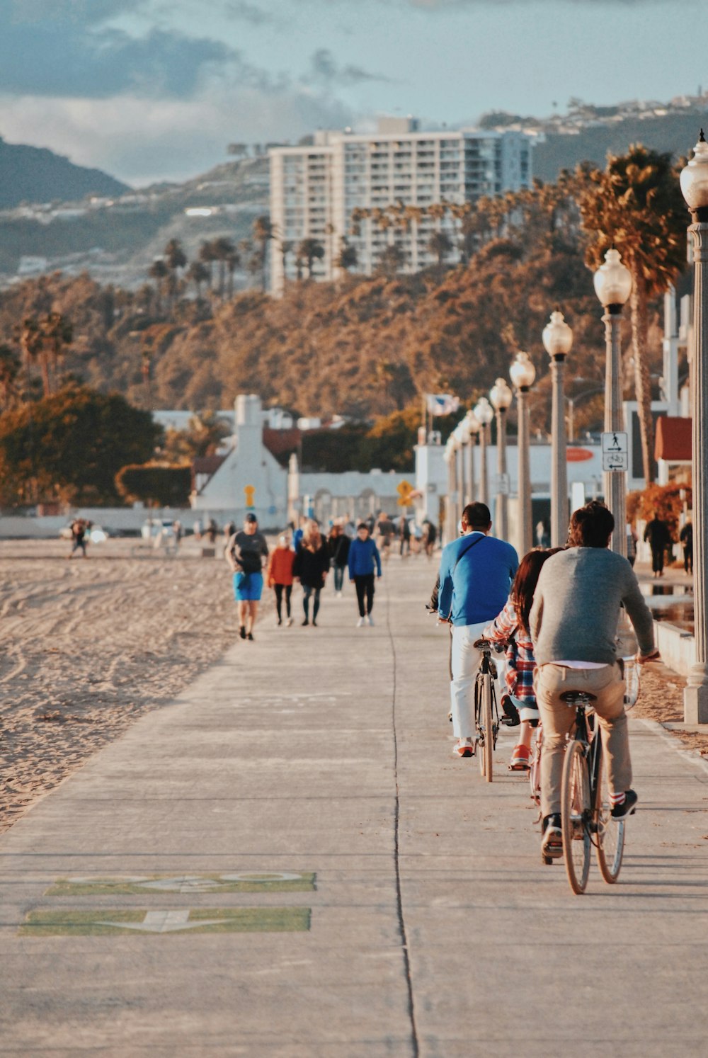 people walking and cycling on concrete pavement near lamp posts during daytime