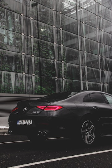 A sleek black car gleaming after a detailed wash, set against a backdrop of a freshly maintained commercial building.