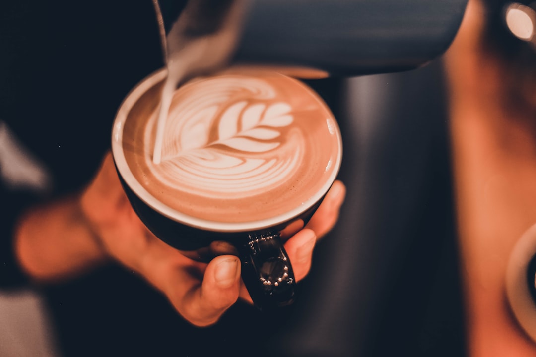 person pouring milk on coffee