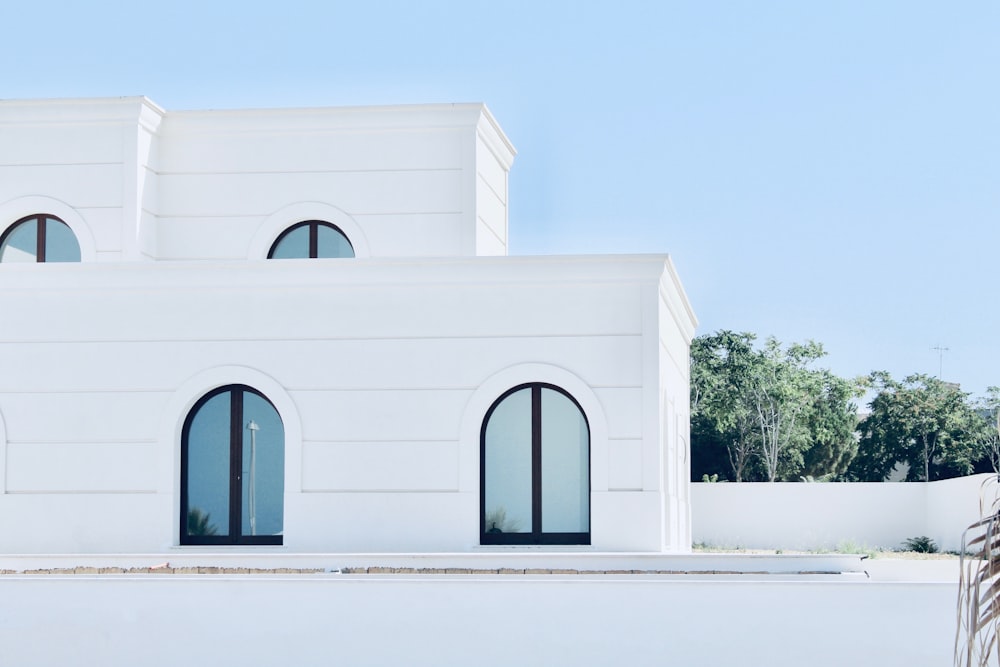 a white building with two windows and a palm tree in front of it