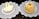 Two pastries are placed on decorative white lace doilies. The left pastry has a light frosting with an orange slice, chopped nuts, and a small green piece of candied fruit. The right pastry is circular and layered, topped with yellow cream, powdered sugar, a red berry, and nuts.