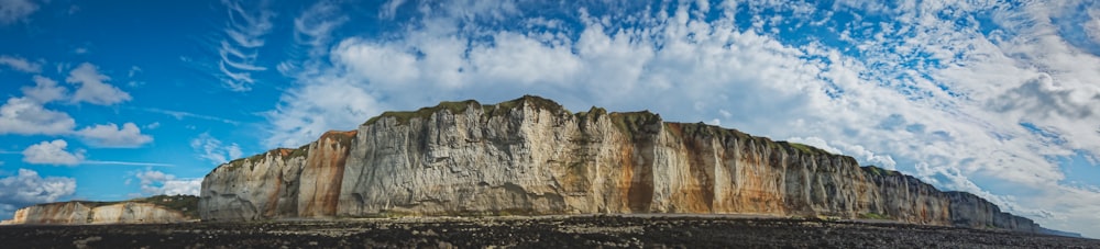 brown rock formation under white and blue cloudy sky