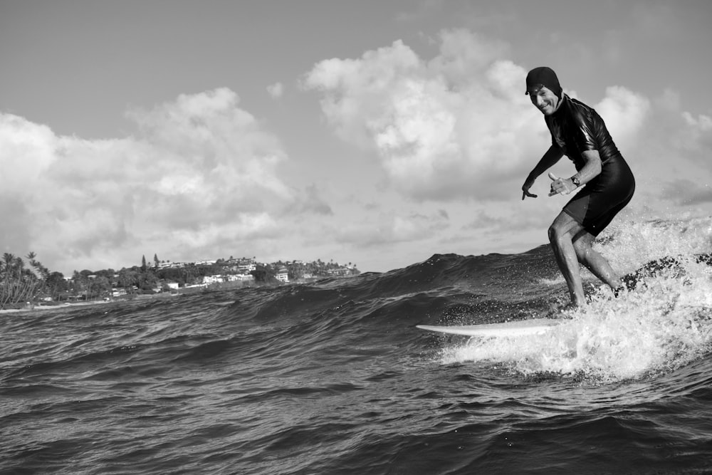 grayscale photo of man riding surfboard during daytime