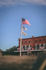 A scenic view of Horseshoe Bend city hall with flags waving under a clear sky.
