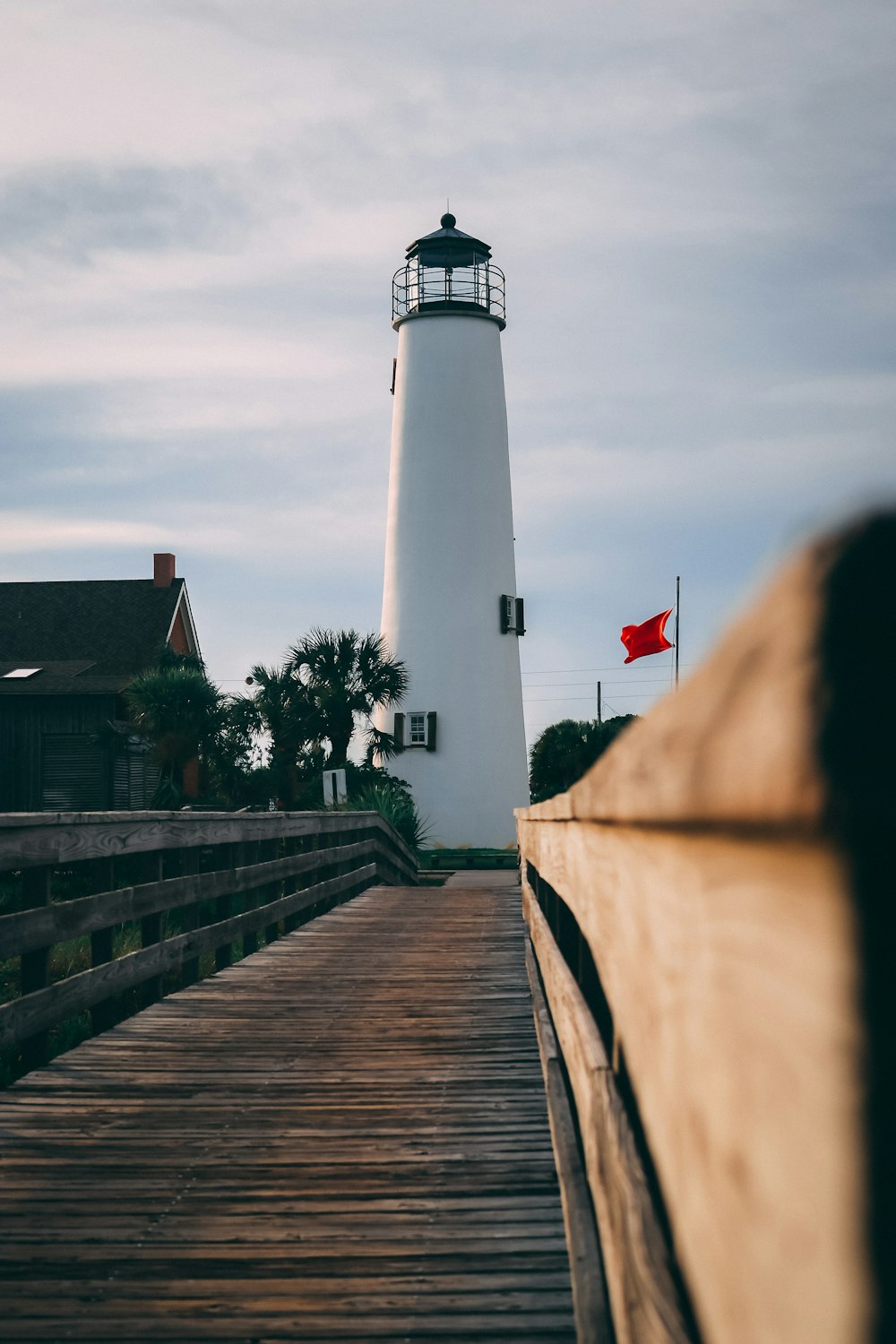 brown wooden bridge near white lighthouse