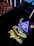 A neon sign with a glowing eye inside a triangle, accompanied by a star and crescent moon motif. Below, the word 'psychic' is illuminated in bright yellow neon. The scene is set against a backdrop of reflective and textured surfaces.
