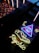 A neon sign with a glowing eye inside a triangle, accompanied by a star and crescent moon motif. Below, the word 'psychic' is illuminated in bright yellow neon. The scene is set against a backdrop of reflective and textured surfaces.