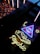 A neon sign with a glowing eye inside a triangle, accompanied by a star and crescent moon motif. Below, the word 'psychic' is illuminated in bright yellow neon. The scene is set against a backdrop of reflective and textured surfaces.