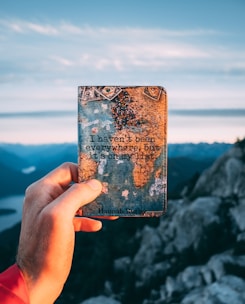 A joyful traveler holding a map with a scenic mountain and city skyline in the background.