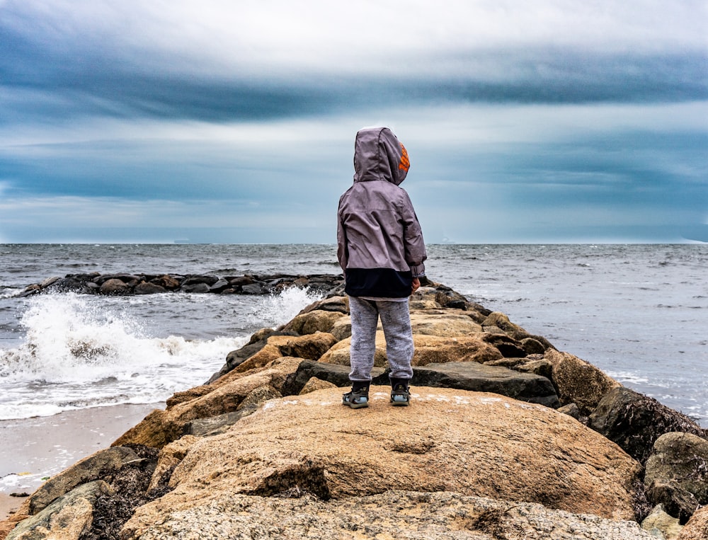 person standing on rock near sea during daytime