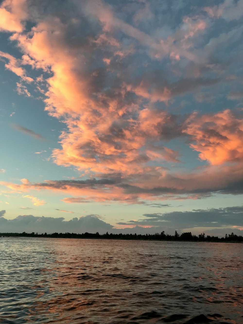 body of water under white and blue cloudy sky during daytime