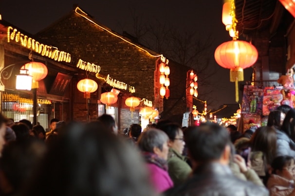 A vibrant street scene in Guangzhou at dusk, with glowing red lanterns and bustling night markets.