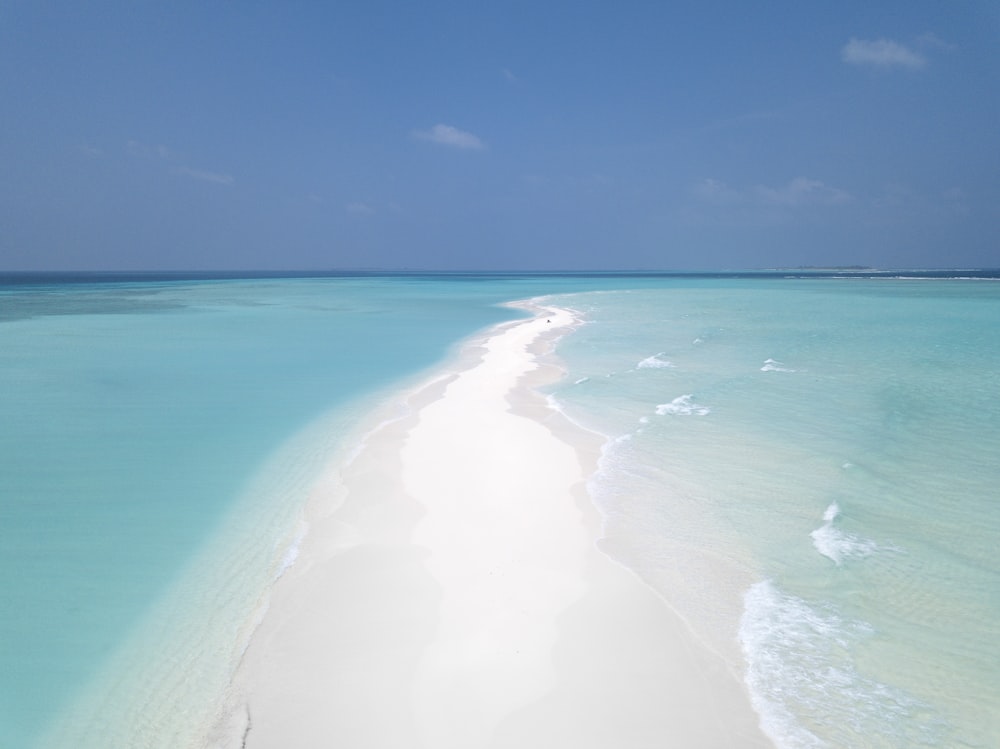 white shore and body of water under blue sky