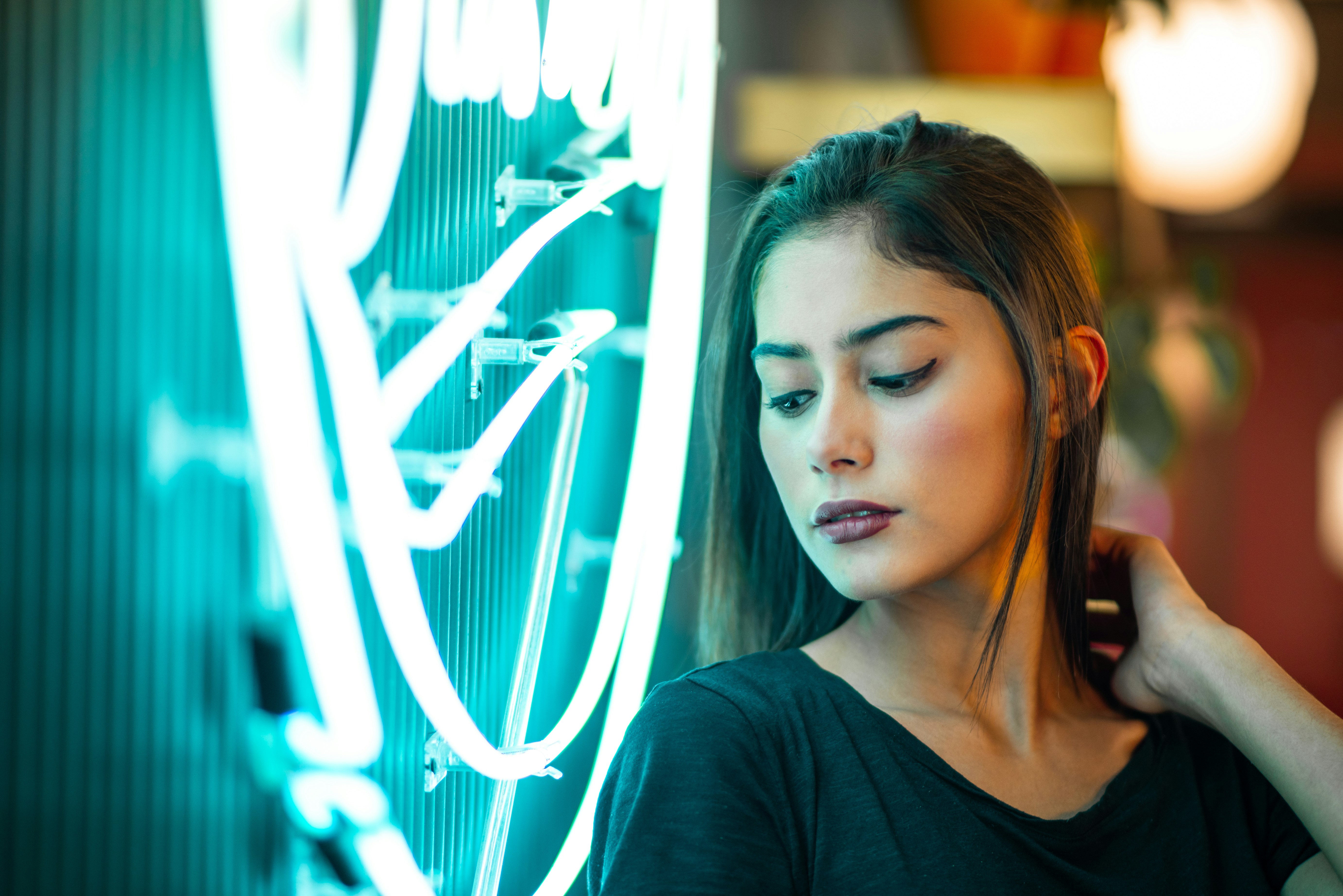 woman wearing black top leaning on neon light signage turned on