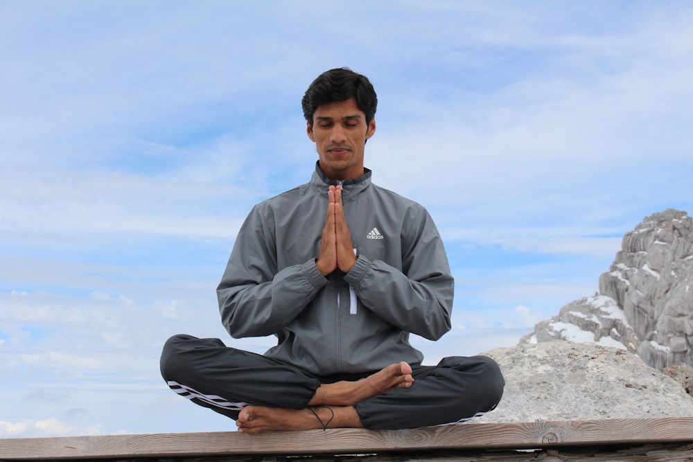 hombre meditando en una plataforma de madera marrón durante el día