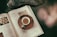 Round image of a steaming cup of tea beside an open book on a wooden table.