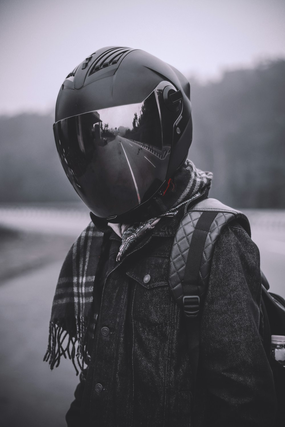 회색조 사진에서 헬멧과 배낭을 착용 한 사람