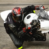 Close-up of a rider wearing a custom leather racing suit gripping the handlebars.