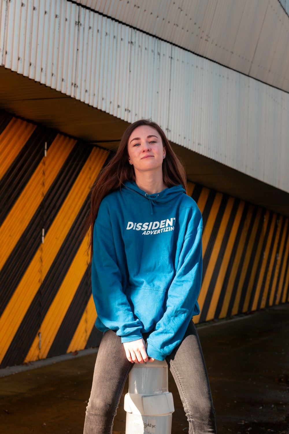 woman in blue hoodie sitting beside wall