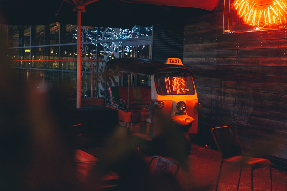 orange and white auto-rickshaw parked beside wooden wall