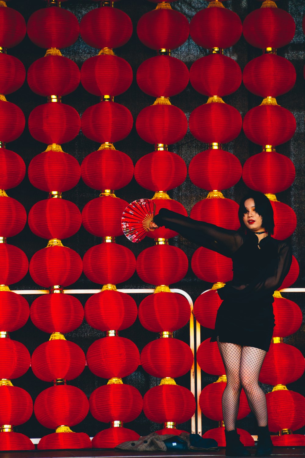 woman wearing black dress holding red hand fan