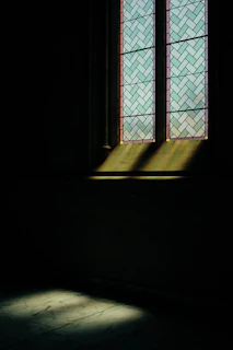 Sunlight filtering through stained glass casting colorful shadows.