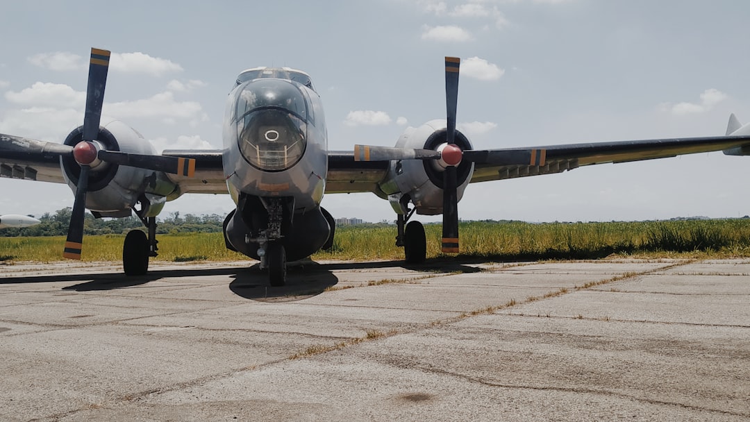 grey twin engine bomber plane on tarmac under cloudy sky,