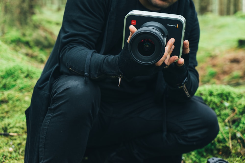 man in black jacket holding DSLR camera