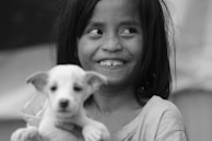 A playful scene with a puppy and a young model laughing together in a sunlit studio.
