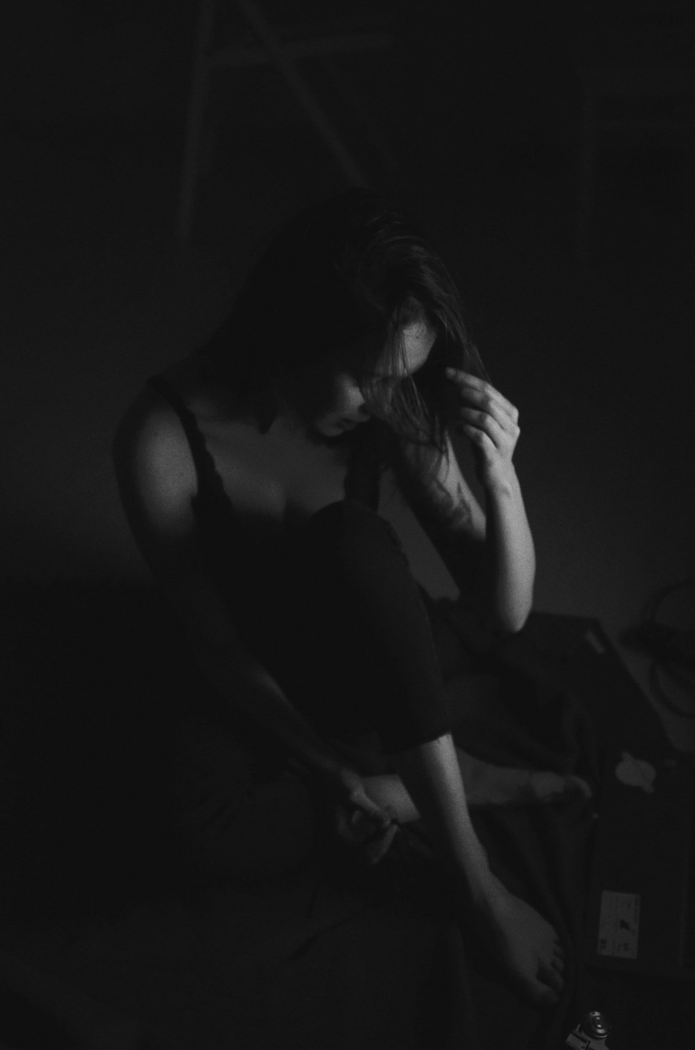 woman in sleeveless shirt sitting on surface in grayscale photography