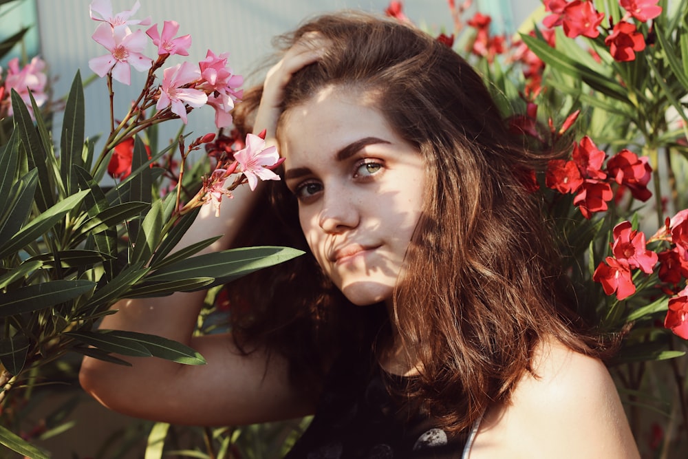 woman surrounded by red and pink petaled flowers