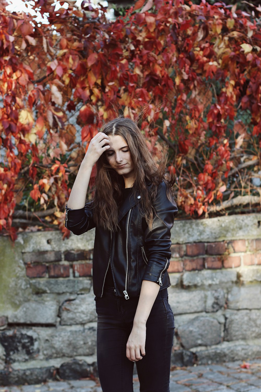 standing woman holding her hair beside tree