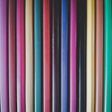 Close-up of colorful pencils neatly arranged on a wooden desk.