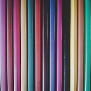 Close-up of a variety of colorful pencils arranged neatly on a wooden desk.