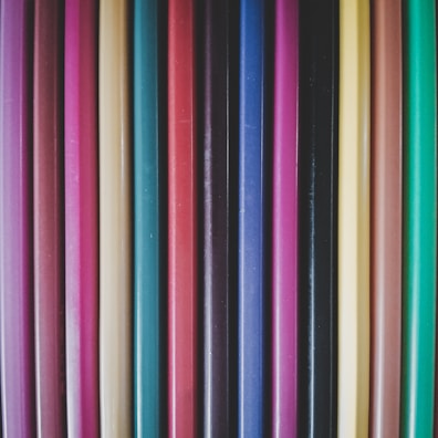 Close-up of colorful pens and pencils arranged neatly on a wooden desk.