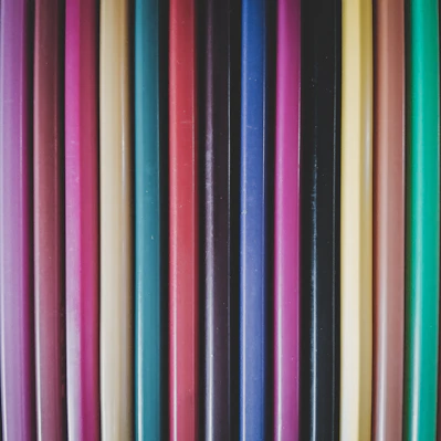A close-up of colorful pens and pencils neatly arranged on a wooden desk.