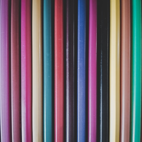 Close-up of colorful pens and pencils neatly arranged on a wooden desk.