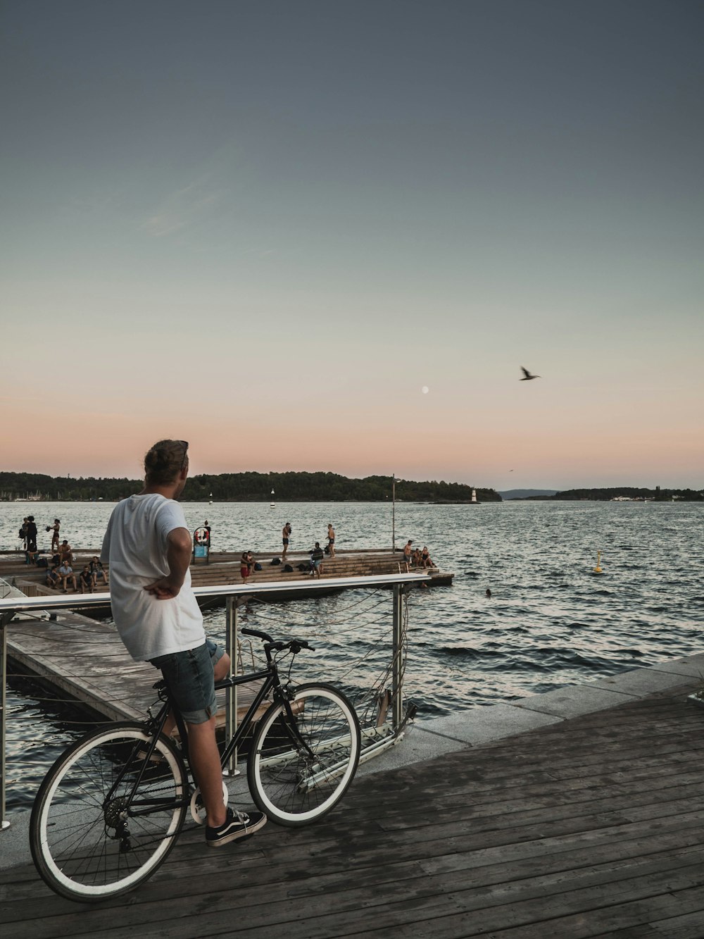 man riding bicycle while watching people on dock during daytime