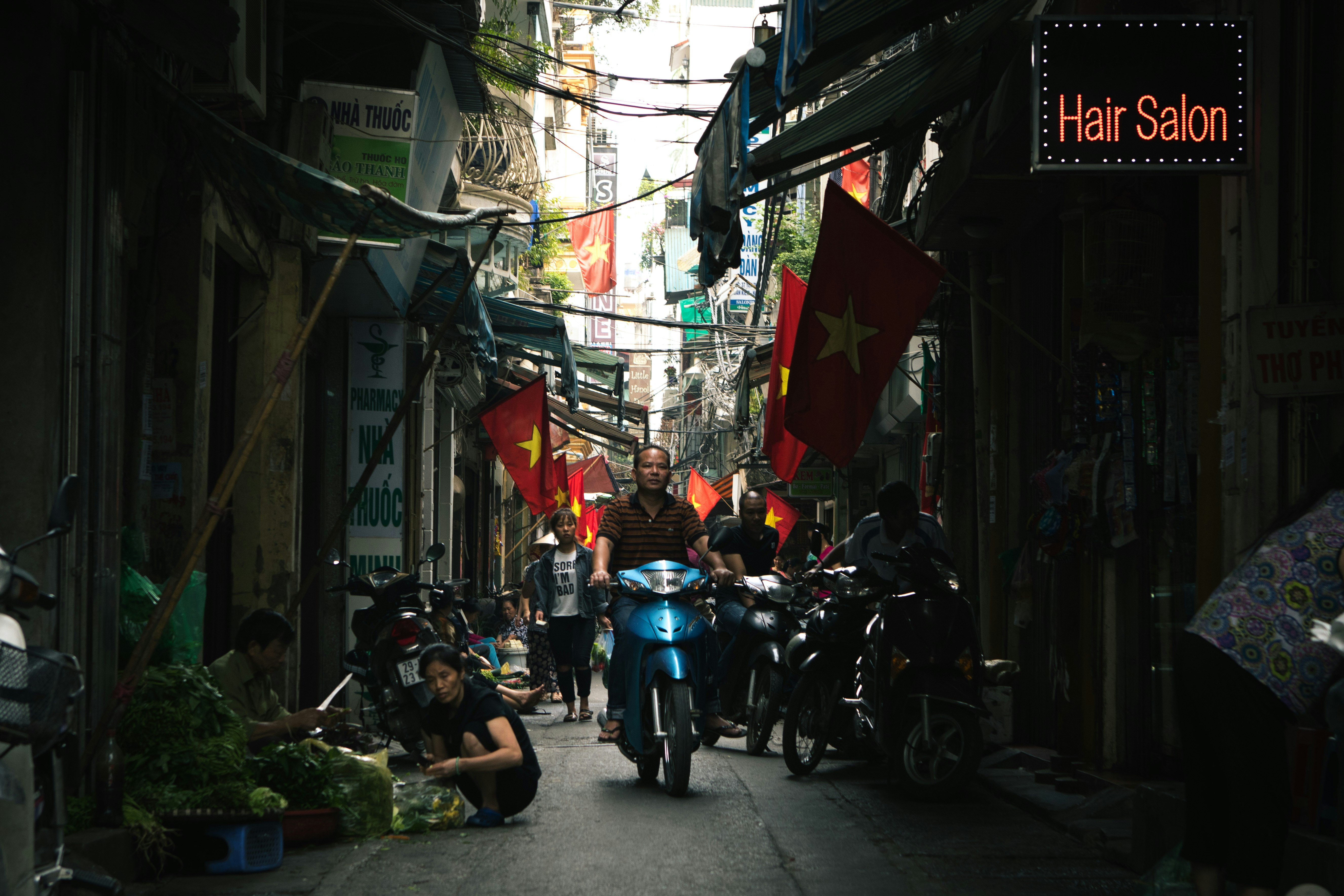 woman driving motorcycle between buildings during daytime