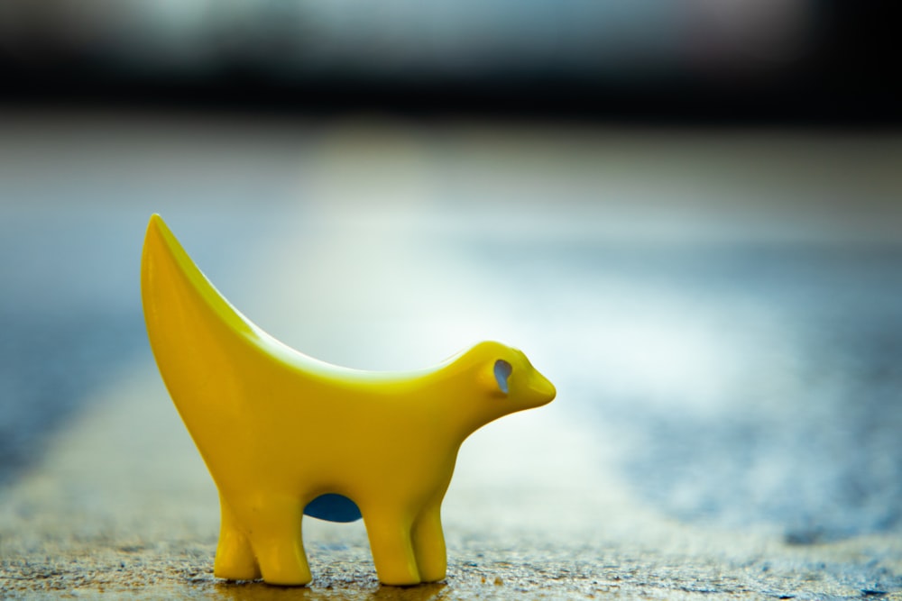 yellow plastic toy on gray pavement in close-up photo