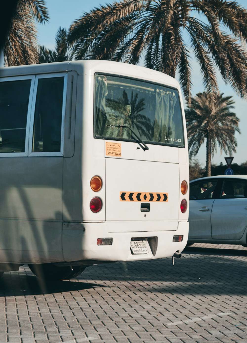 Autobús blanco estacionado junto a sedán blanco durante el día
