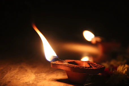 Close-up of a detailed brass diya lamp glowing softly in warm light.
