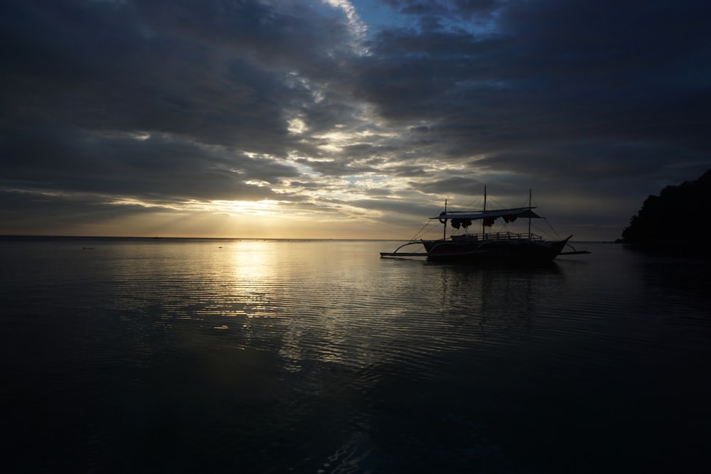 boat on water under gray skies during golden hour