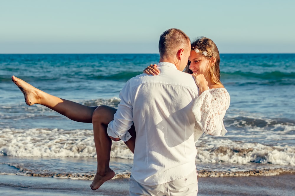 man carrying woman on seashore