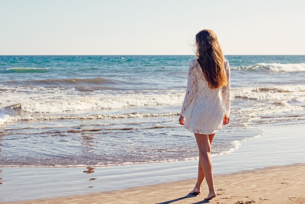 woman walking on shore with bare foot during daytime