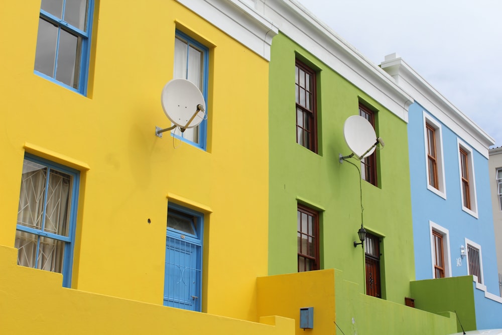 포물선 안테나가 있는 노란색과 녹색 콘크리트 건물의 저각 사진