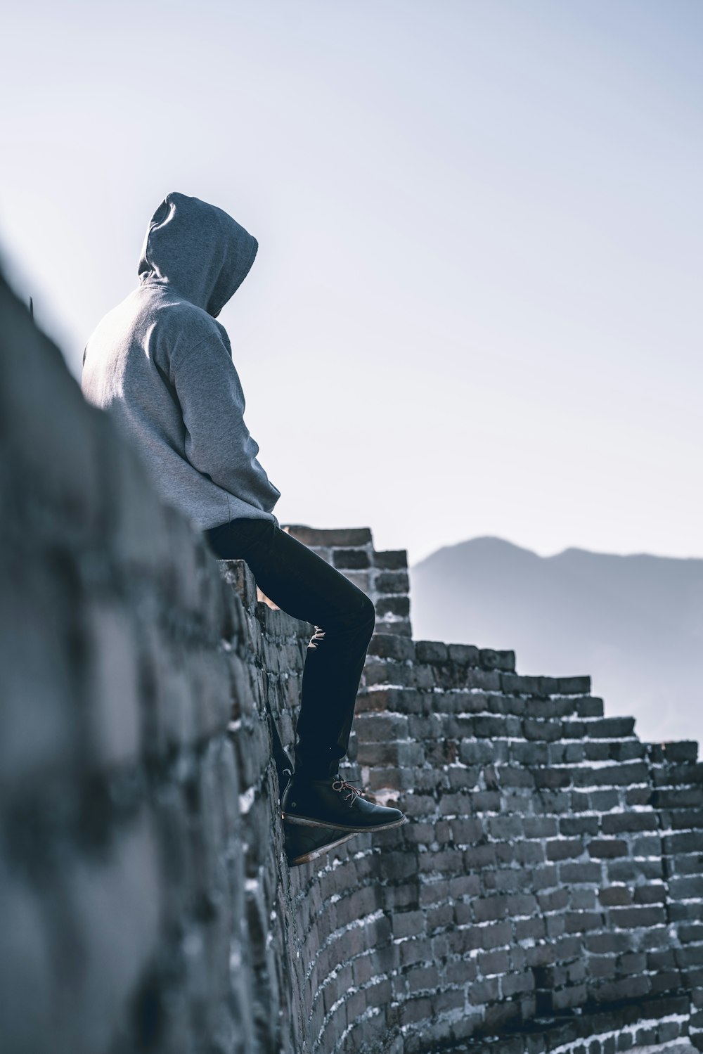 person sitting on brick wall fence during daytime