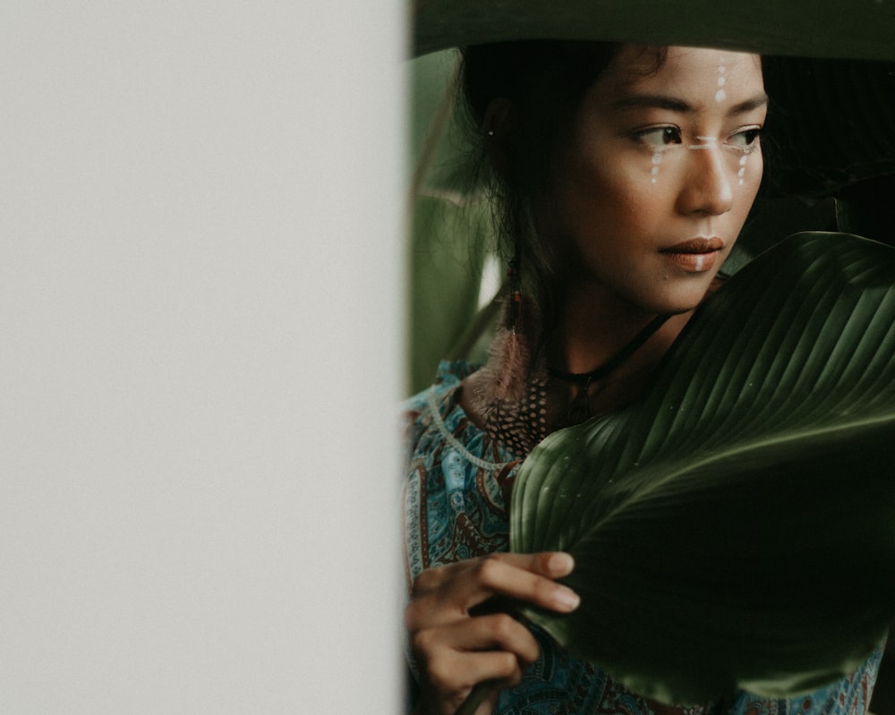 woman taking selfie behind green leaf