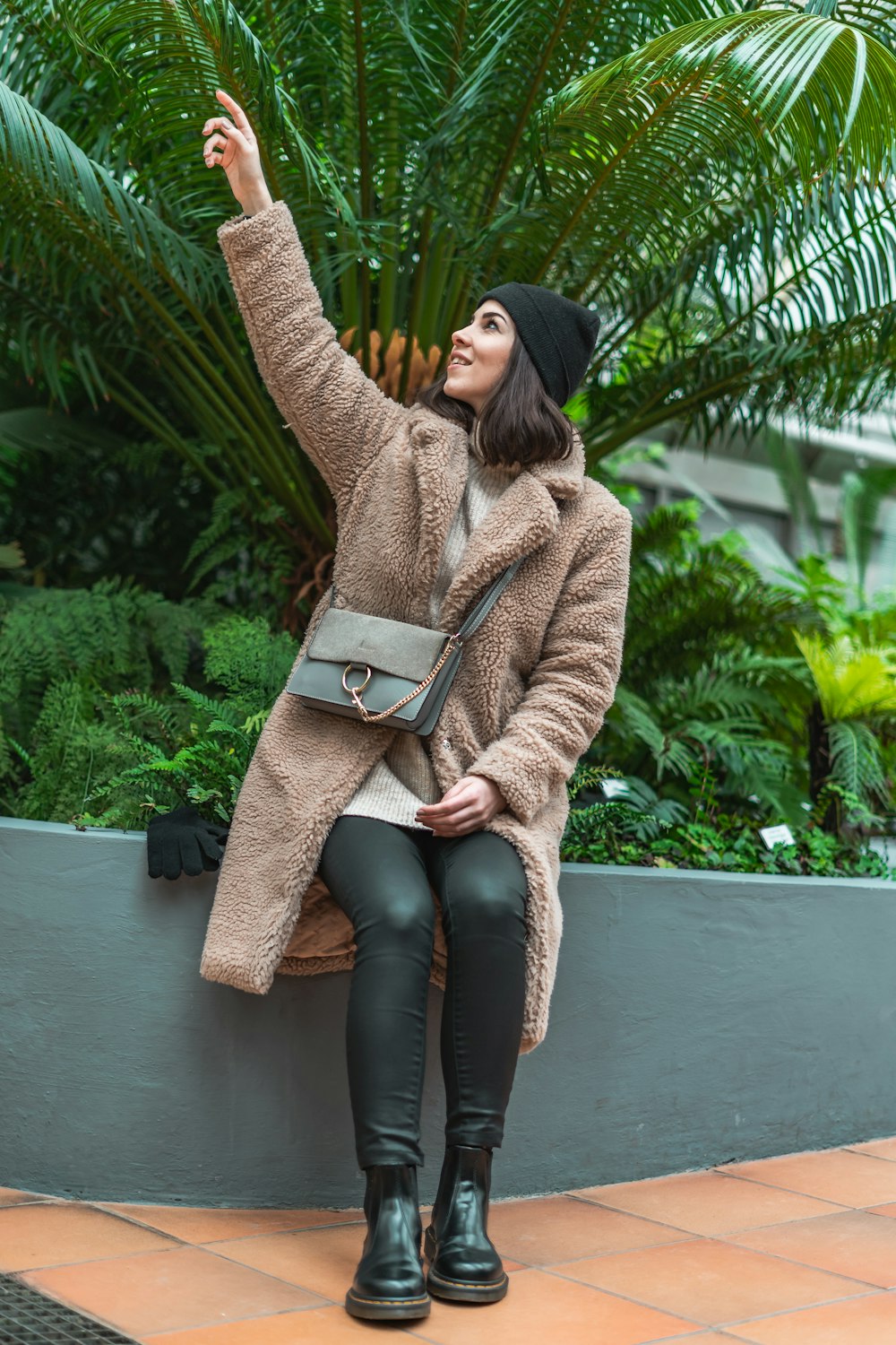 woman sitting on concrete pavement while raising her right hand