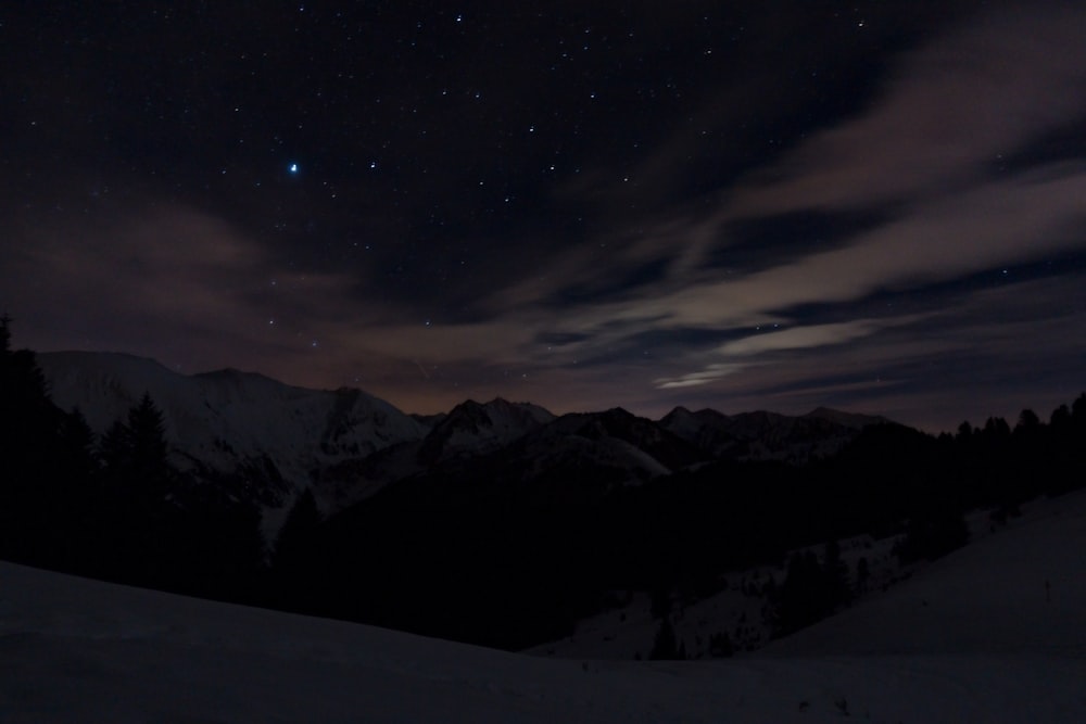 gray and white mountain hill under starry night